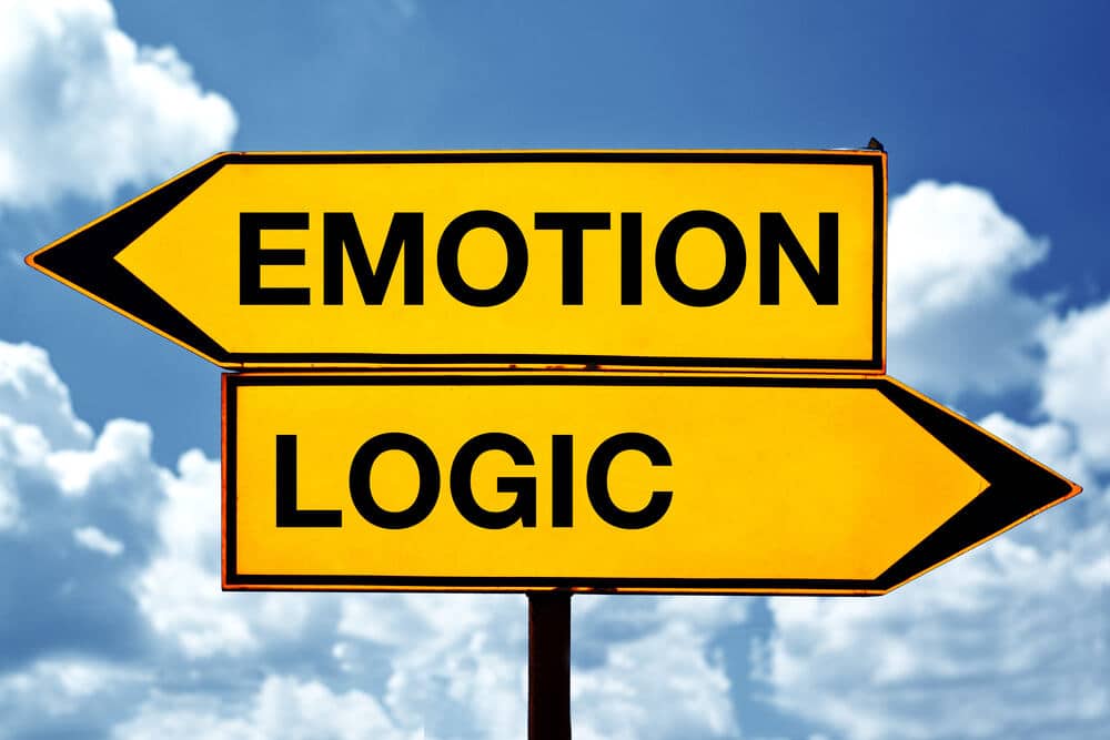 Two yellow road signs, the one pointing left reads, "Emotion" and the one pointing right reads, "Logic". 