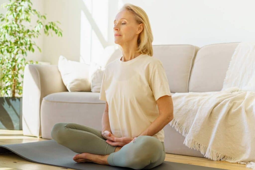 relaxed woman sitting in a lotus position as does deep breathing exercises